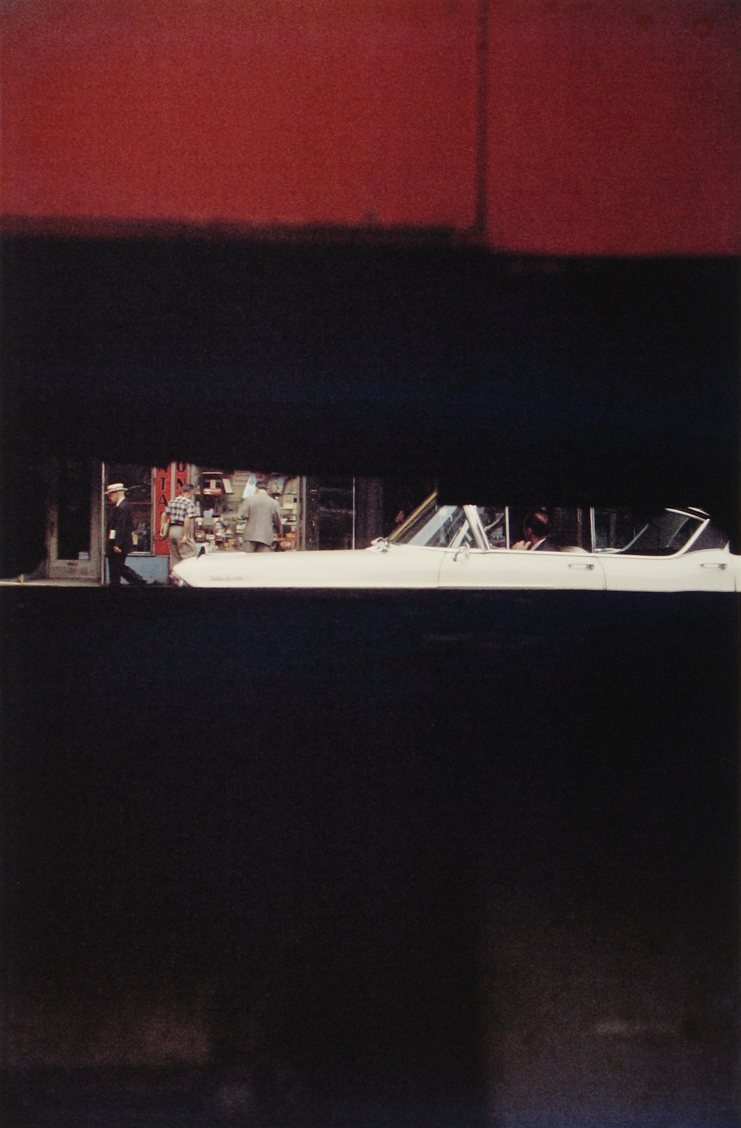 A red band, a black band, and a thin strip of street with a white convertible and three men.